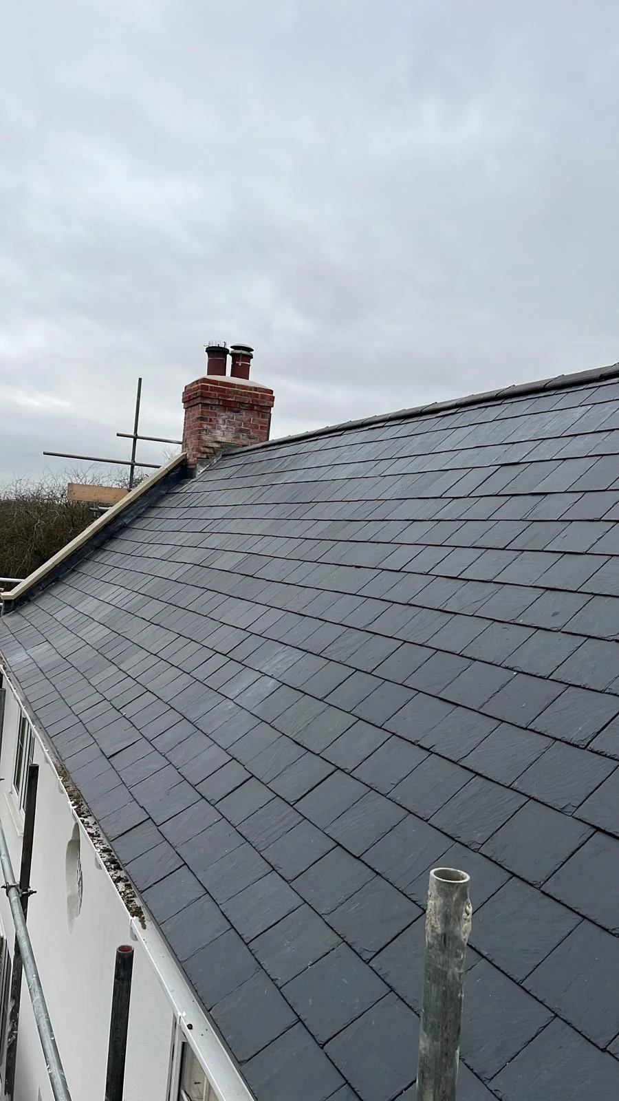 Broad slate roof slope with chimney and scaffold access