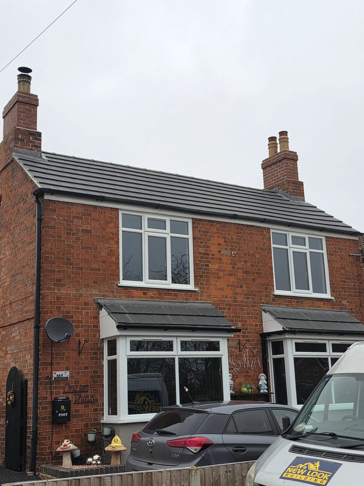 Tiled roof and twin chimneys above a brick house