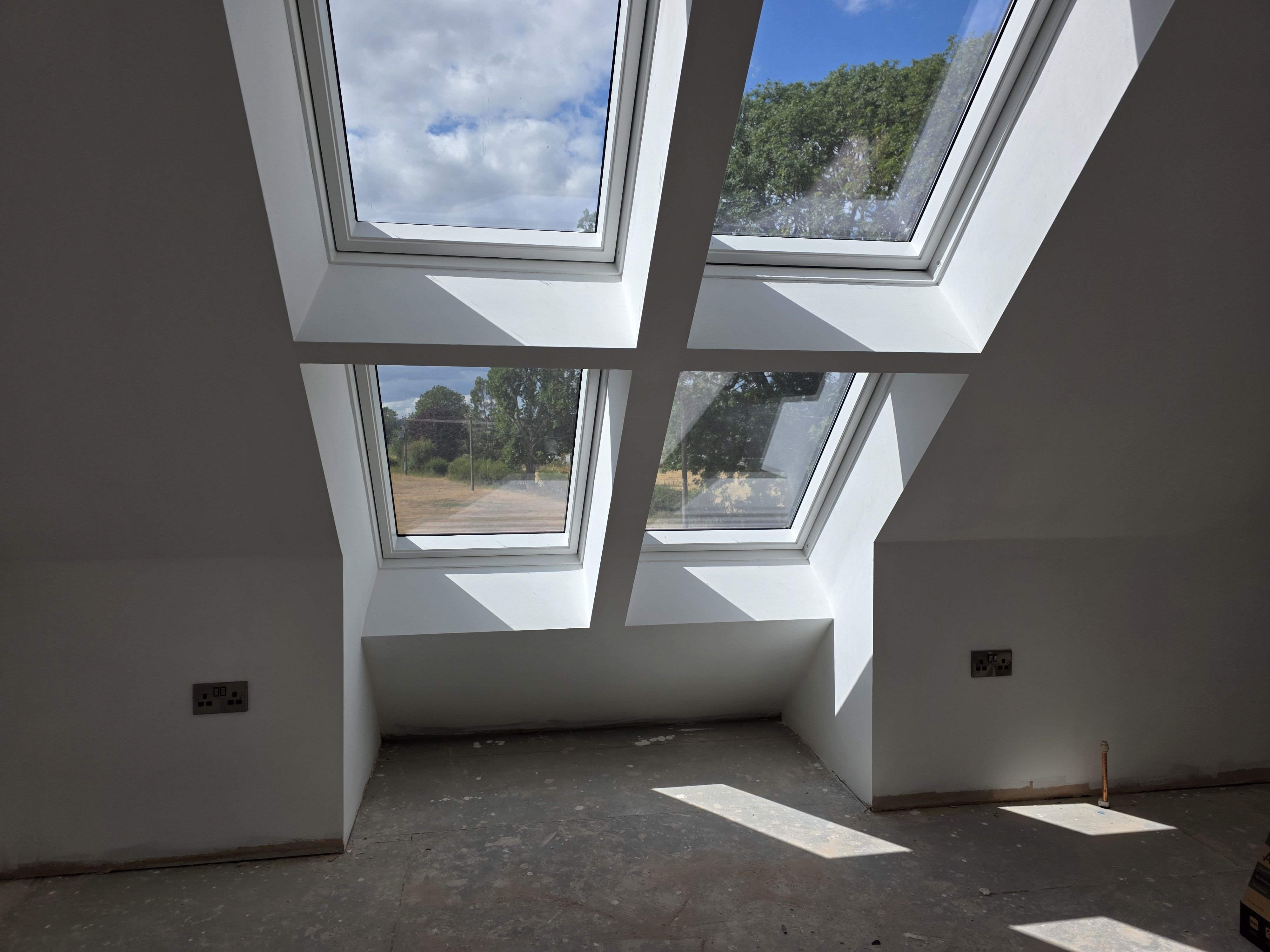 Loft conversion room with new sockets beneath the roof windows